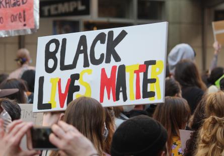 Protest march. Sign reading "Black lives Matter" in Aboriginal flag colours