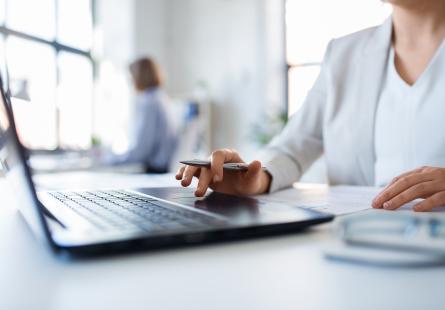 A businessperson sits working at a laptop computer
