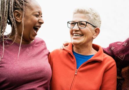 Two middle-aged people stand close together smiling and laughing