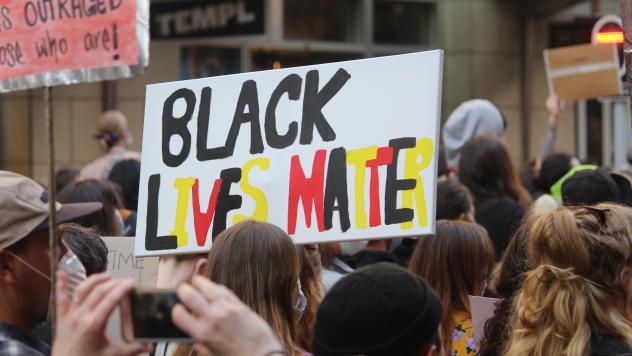 Protest march. Sign reading "Black lives Matter" in Aboriginal flag colours